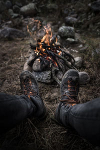 Low section of man wearing shoes by campfire on field