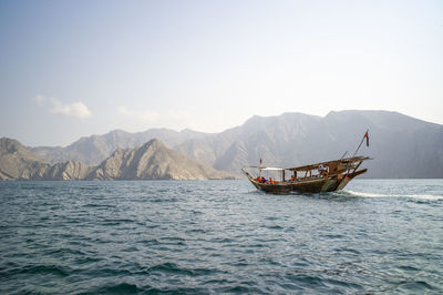 Fishing boat in sea against mountains