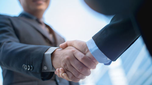 Midsection of businessman and colleague shaking hands at office