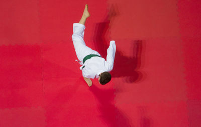 Directly above shot of boy practicing karate on red floor