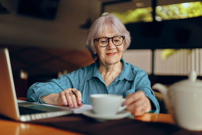 Smiling senior woman holding coffee cup in cafe