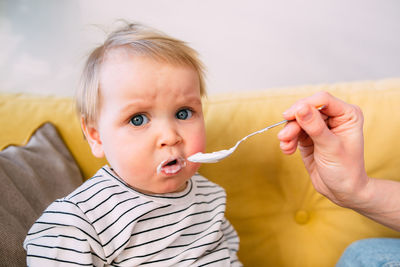 Mom feeds a small child at home with yogurt from a spoon. family concept