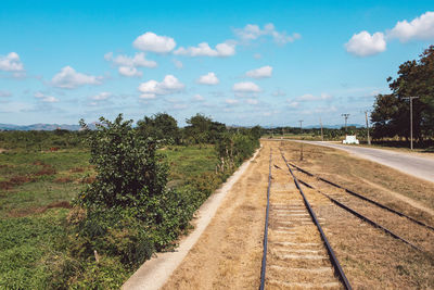 Empty railroad track amidst field against sky