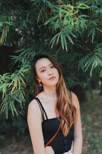 Portrait of beautiful young woman standing against plants