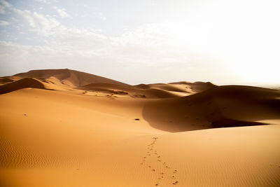 Sand dunes in desert against sky