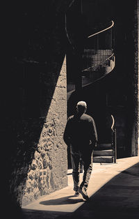 Rear view of man walking on footpath in city