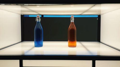 Close-up of wine bottles on table against wall