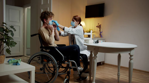 Doctor wearing mask examining patient at home