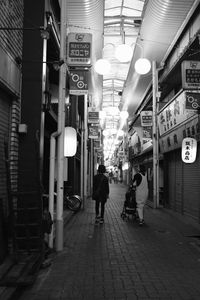 People walking on illuminated street amidst buildings in city