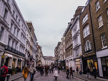 People walking on street amidst buildings in city