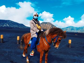 Man riding horse on mountain against sky