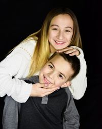 Portrait of brother and sister against black background