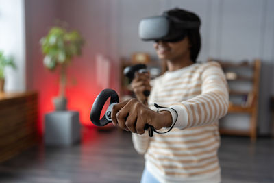 Excited afro woman wear vr glasses hold joystick experience of virtual reality headset, soft focus