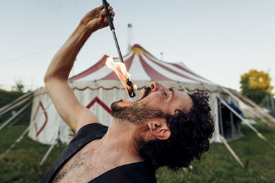 Male fire-eater practicing outside circus tent