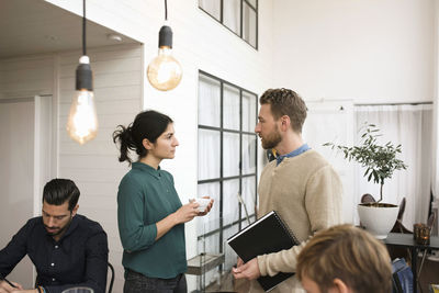 Businesswoman talking with man while colleagues working at office