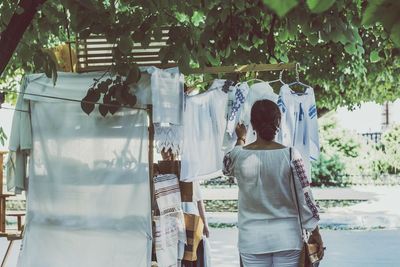 Rear view of woman touching clothes hanging at market stall