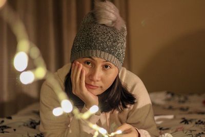 Portrait of woman wearing hat while holding lighting equipment at home