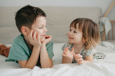 Older brother and younger sister playing in the bedroom on the bed. high quality photo