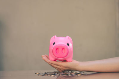 Midsection of woman holding pink flower against black background