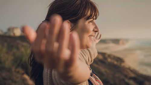 Smiling young woman with arms outstretched standing outdoors