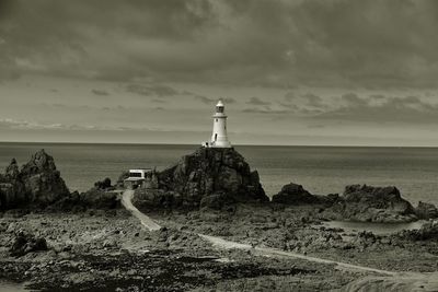 Lighthouse by sea against sky