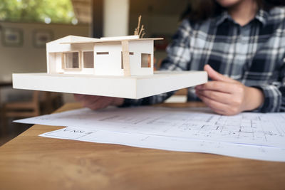 Midsection of man holding paper on table