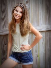 Portrait of smiling young woman standing against curtain