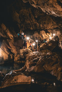 People at illuminated rock formation in water