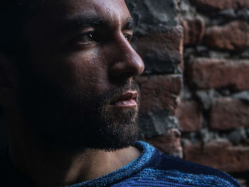 Portrait of young man looking away against wall