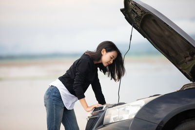 Woman repairing car engine on road