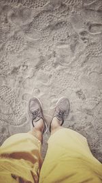 Low section of man standing on sand