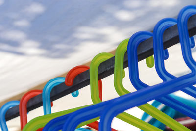 Numerous colourful plastic clothes hangers on a clothes rail