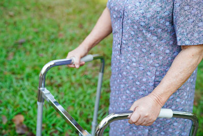 Midsection of person holding bicycle against plants