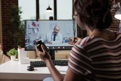 Rear view of woman using laptop at office