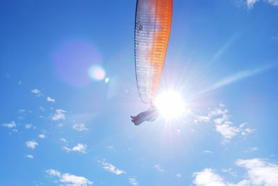 Low angle view of bird flying against bright sun