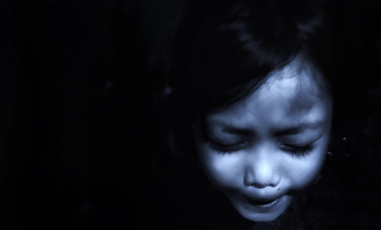 CLOSE-UP PORTRAIT OF CUTE GIRL IN DARK ROOM