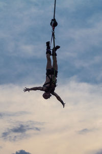 Low angle view of man skateboarding on rope against sky