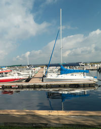 Sailboats moored at harbor against sky