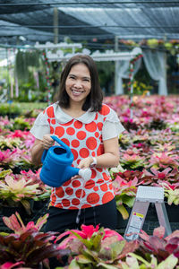 Portrait of a smiling young woman standing in greenhouse