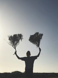 Rear view of silhouette woman standing on field against sky