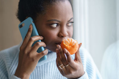 Woman smelling orange while talking over phone