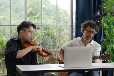 Two musician practice live playing guitar and violin together at home