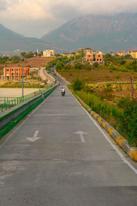 Road by buildings in city against sky