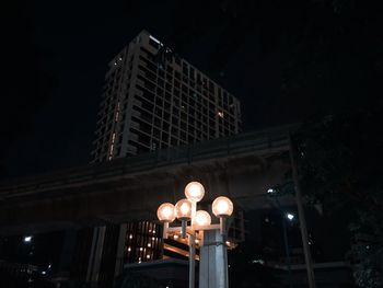 Low angle view of illuminated street light against building at night