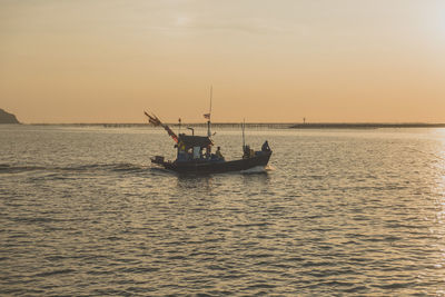 Boat sailing in sea against sky during sunset