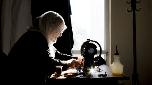 Side view of woman preparing food on table at home