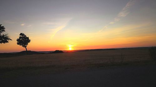 Scenic view of silhouette field against sky during sunset