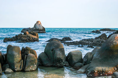 Rocks on beach against clear sky