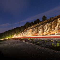 Light trails on road against sky at night