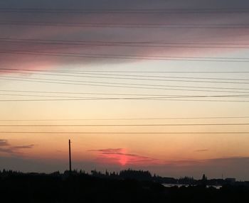 Silhouette electricity pylon against sky at sunset